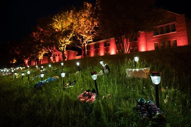 Shoes are placed on the lawn outside the former Kamloops Indian Residential School to honour 215 children after it was announced that ground-penetrating radar had detected unmarked graves near the facility in Kamloops, B.C., on June 4, 2021. THE CANADIAN PRESS/Darryl Dyck