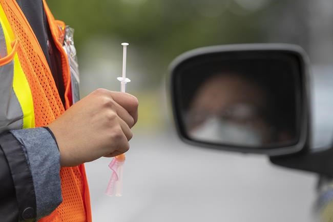 A person waits to receive their COVID-19 vaccine during a drive-thru clinic at Richardson stadium in Kingston, Ont., Friday, July 2, 2021. Canada is facing a potential wave of terminations tied to mandatory workplace vaccine policies as a growing number of employers require workers to be fully inoculated against COVID-19 -- or risk losing their jobs, legal experts say. THE CANADIAN PRESS/Lars Hagberg