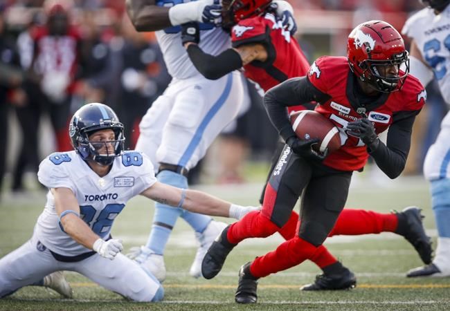 Toronto Argonauts' Jimmy Ralph, left, looks on as Calgary Stampeders' Tre Roberson, picks up a fumbled ball and runs it in for a touchdown during second half CFL football action in Calgary, Thursday, July 18, 2019. THE CANADIAN PRESS/Jeff McIntosh