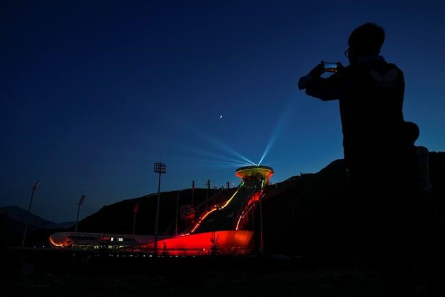 A reporter uses his smartphone to film a light show at the National Ski Jumping Centre, one of the venues for Beijing 2022 Olympic and Paralympic Winter Games, during a media tour in Zhangjiakou in northwestern China's Hebei province on Wednesday, July 14, 2021. Canada's Olympic and Paralympic athletes must be vaccinated to compete at the 2022 Winter Games in Beijing. THE CANADIAN PRESS/AP/Andy Wong