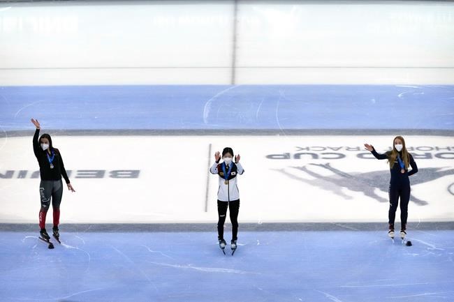 From left, silver medalist Courtney Sarault of Canada, gold medalist Lee Yu-bin of South Korea, and bronze medalist Kristen Santos of the United States wave during the medal ceremony for women's 1500m at the ISU World Cup Short Track speed skating competition, a test event for the 2022 Winter Olympics, at the Capital Indoor Stadium in Beijing, Saturday, Oct. 23, 2021. THE CANADIAN PRESS/AP-Mark Schiefelbein