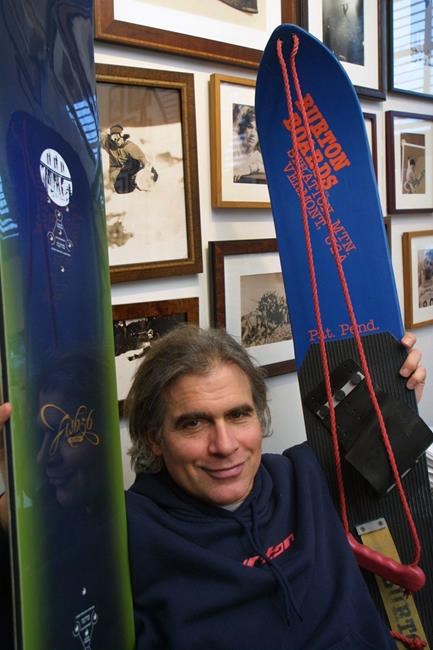 FILE - In this March 8, 2002, file photo, Jake Burton Carpenter, owner of Burton Snowboards, shows an early model, right, and one of the newer snowboards, left, in his office in Burlington, Vt. A new documentary on the late snowboarding pioneer Jake Burton is more than a glossy retrospective of his life. It's a raw, unflinching examination of the trials and tribulations Burton went through over a four-decade career in which he shaped both the snowboard and the the billion-dollar industry that forever changed life on the mountain. The movie: “Dear Rider: The Jake Burton Story,” premieres on HBO on Nov. 9, 2021. (AP Photo/Alden Pellett, File)