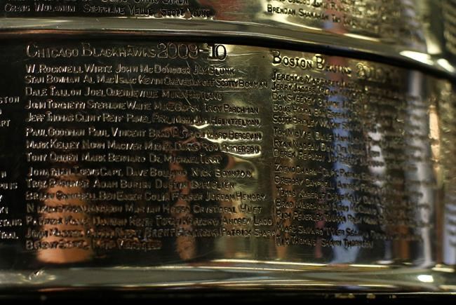 FILE - The names of the 2010 Stanley Cup Champion Chicago Blackhawks, left, are displayed on the Stanley Cup in the lobby of the United Center during an NHL hockey news conference on June 11, 2013 in Chicago. The first game of the Stanley Cup final series is Wednesday in Chicago. Blackhawks owner Rocky Wirtz wants the Hockey Hall of Fame to cover the name of an assistant coach engraved on the Stanley Cup after the assistant was accused of sexually assaulting a player during the team's run to the 2010 championship. (AP Photo/Charles Rex Arbogast, File)