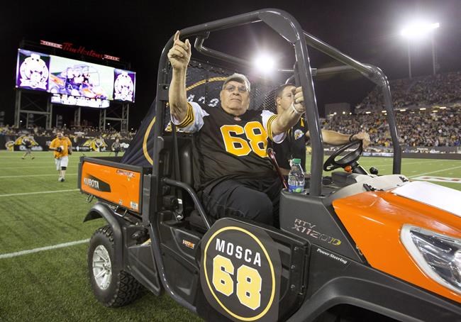 Hamilton Tiger-Cats alumnus Angelo Mosca, centre, is driven out onto the field in Hamilton, Ont., Thursday, Aug. 27, 2015. The often colourful Mosca died Saturday at the age of 84. THE CANADIAN PRESS/Peter Power