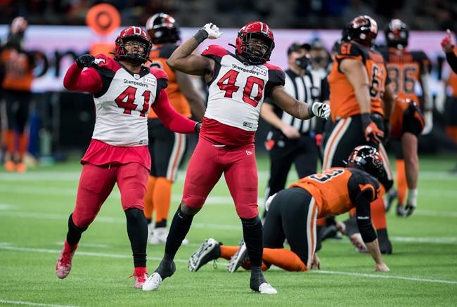 Calgary Stampeders' Mike Rose (41) and Shawn Lemon (40) celebrate after Lemon forced B.C. Lions quarterback Michael Reilly, back right, to fumble the ball leading to a turnover during the second half of a CFL football game in Vancouver, on Friday, November 12, 2021. THE CANADIAN PRESS/Darryl Dyck