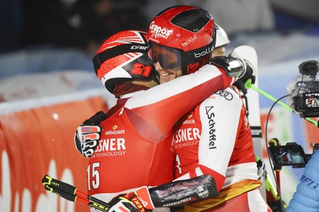 Austria's Christian Hirschbuehl, left, winner of an alpine ski, men's World Cup parallel event, hugs second-placed Austria's Dominik Raschner, in Lech/Zuers, Austria, Sunday, Nov. 14, 2021. (AP Photo/Marco Trovati)