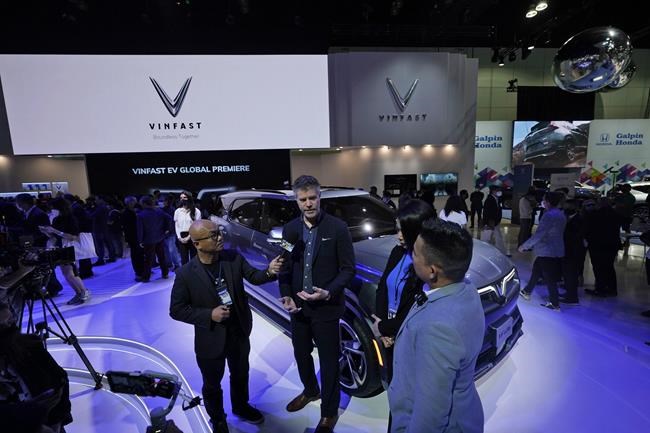 VinFast Chief Design Officer David Lyon fields questions after introducing the company's new EV, the VF e36, behind him, at the AutoMobility LA Auto Show Wednesday, Nov. 17, 2021, in Los Angeles. (AP Photo/Marcio Jose Sanchez)