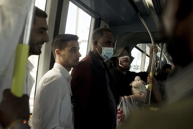 A man who opposes coronavirus vaccine mandates wears a mask altered to make a statement, while carrying a toy sheep and an outsized syringe as he rides a crowded train in Jerusalem ahead of Shabbat, Friday, Nov. 26, 2021. Israel's prime minister says it is