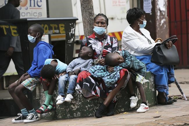 A mother takes time to rest with her children in Harare, Zimbabwe, Friday, Nov, 26, 2021. A slew of nations have moved to stop air travel from southern Africa, and stocks have plunged in Asia and Europe in reaction to news of a new, potentially more transmissible COVID-19 variant. (AP Photo/Tsvangirayi Mukwazhi)