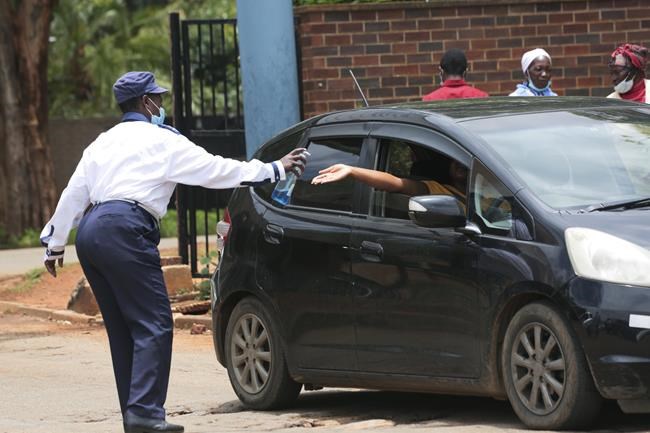 A security guard santizes a motorist's hands, at the entrance of a health facilty in Harare, Zimbabwe, Friday, Nov, 26, 2021. A slew of nations have moved to stop air travel from southern Africa, and stocks have plunged in Asia and Europe in reaction to news of a new, potentially more transmissible COVID-19 variant. (AP Photo/Tsvangirayi Mukwazhi) /