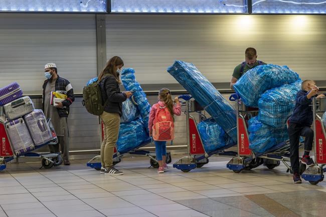 People line up to get on an overseas flight at OR Tambo International Airport in Johannesburg, South Africa, Friday Nov. 26, 2021. A slew of nations moved to stop air travel from southern Africa on Friday in reaction to news of a new, potentially more transmissible COVID-19 variant that has been detected in South Africa. Scientists say it is a concern because of its high number of mutations and rapid spread among young people in Gauteng, the country's most populous province. (AP Photo/Jerome Delay)