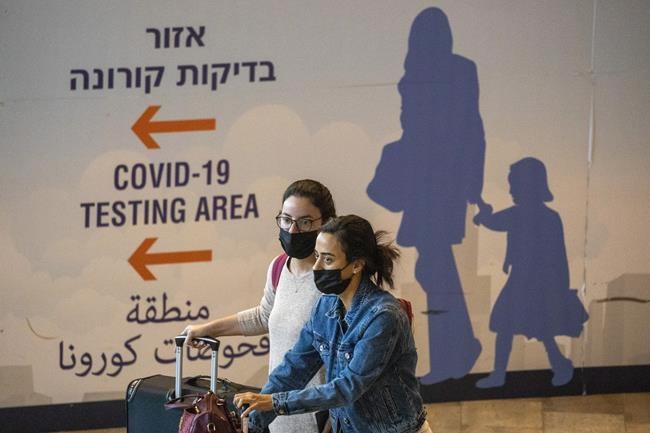 Travelers wearing protective face masks arrive at the Ben Gurion Airport near Tel Aviv, Israel, Sunday, Nov. 28, 2021. Israel on Sunday approved barring entry to foreign nationals and the use of controversial technology for contact tracing as part of its efforts to clamp down on a new coronavirus variant. (AP Photo/Ariel Schalit)