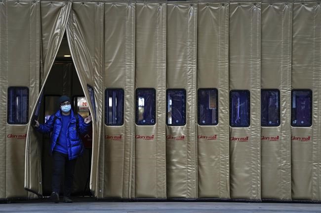 A man wearing a face mask to help curb the spread of the coronavirus walks out from a shopping mall in Beijing, Monday, Nov. 29, 2021. Cases of the omicron variant of the coronavirus popped up in countries on opposite sides of the world Sunday and many governments rushed to close their borders even as scientists cautioned that it's not clear if the new variant is more alarming than other versions of the virus. (AP Photo/Andy Wong)