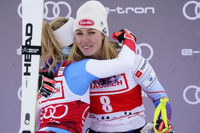 First placed Switzerland's Lara Gut-Behrami, left, hugs United States' Mikaela Shiffrin, third placed on the podium of an alpine ski, women's World Cup super-G in St. Moritz, Switzerland, Saturday, Dec. 11, 2021. (AP Photo/Pier Marco Tacca)