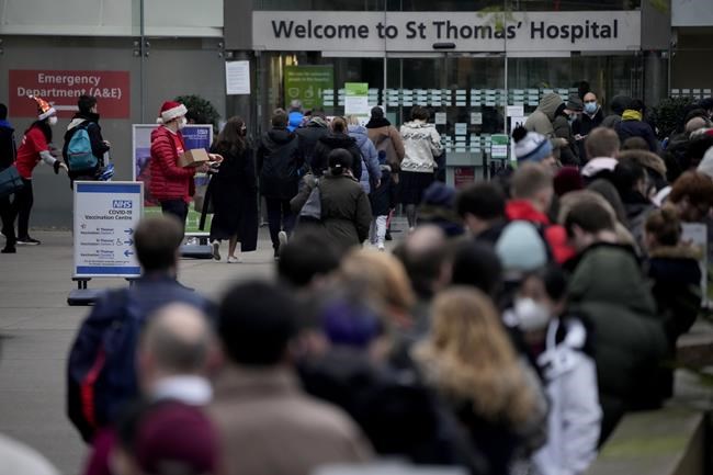 People queue up, at right, for coronavirus booster jabs at St Thomas' Hospital, in London, Tuesday, Dec. 14, 2021. Long lines have formed for booster shots across England as the U.K. government urged all adults to protect themselves against the omicron variant. (AP Photo/Matt Dunham)