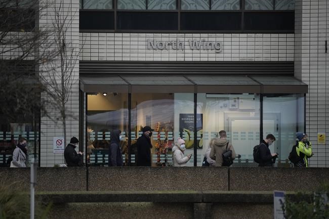 People queue for coronavirus booster jabs at St Thomas' Hospital, in London, Tuesday, Dec. 14, 2021. Long lines have formed for booster shots across England as the U.K. government urged all adults to protect themselves against the omicron variant. (AP Photo/Matt Dunham)