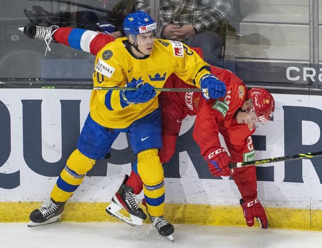 Sweden's Albert Sjöberg fights for control of the puck with Russia's Yegor Savikov during second period IIHF World Junior Hockey Championship action in Red Deer, Alberta on Sunday, December 26, 2021. THE CANADIAN PRESS/Jonathan Hayward
