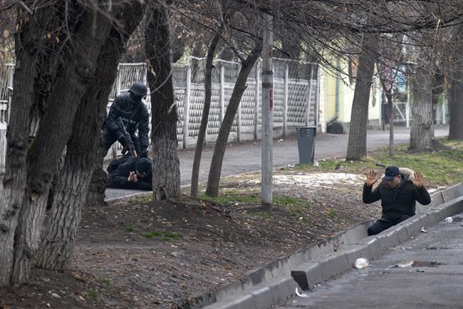 An armed riot police officer detains two protesters during a security anti-terrorists operation in a street after clashes in Almaty, Kazakhstan, Saturday, Jan. 8, 2022. Kazakhstan's president authorized security forces on Friday to shoot to kill those participating in unrest, opening the door for a dramatic escalation in a crackdown on anti-government protests that have turned violent. The Central Asian nation this week experienced its worst street protests since gaining independence from the Soviet Union three decades ago, and dozens have been killed in the tumult. (AP Photo/Vasily Krestyaninov)
