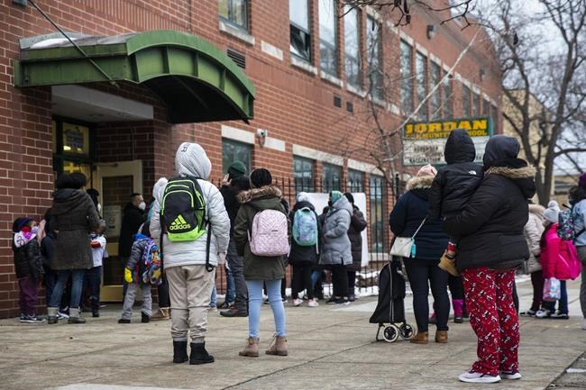 Students and parents arrive at Jordan Community Public School in Rogers Park on the North Side, Wednesday, Jan. 12, 2022 in Chicago. Students returned to in-person learning Wednesday after a week away while the Chicago Public Schools district and the Chicago Teachers Union negotiated stronger COVID-19 protections. (Ashlee Rezin /Chicago Sun-Times via AP)