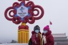 Women wearing face masks printed with a slogan for Beijing Winter Olympics Games take a selfie with a decoration for the Winter Olympics Games on Tiananmen Square in Beijing, Thursday, Jan. 20, 2022. With just over two weeks before the opening of the Beijing Winter Olympics, residents of the Chinese capital say they're disappointed at not being able to attend events because of coronavirus restrictions that have seen parts of the city placed under lockdown. (AP Photo/Andy Wong)