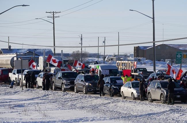 Protesters of COVID-19 restrictions and supporters of Canadian truck drivers protesting the COVID-19 vaccine mandate cheer on a convoy of trucks headed to Ottawa on the Trans-Canada Highway west of Winnipeg, Tuesday, Jan. 25, 2022. THE CANADIAN PRESS/David Lipnowski