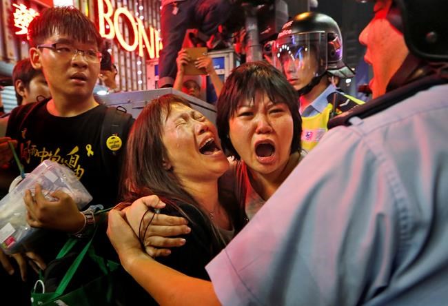 FILE - Protesters cry as the police officers try to stop them blocking the road in Mong Kok district of Hong Kong Wednesday Nov. 26, 2014. As Beijing prepares to hold the Winter Olympics opening in February 2022, China's president and party leader Xi Jinping appears firmly in control. The party has made political stability paramount and says that has been the foundation for the economic growth that has bettered lives and put the nation on a path to becoming a regional if not global power. (AP Photo/Kin Cheung, File)