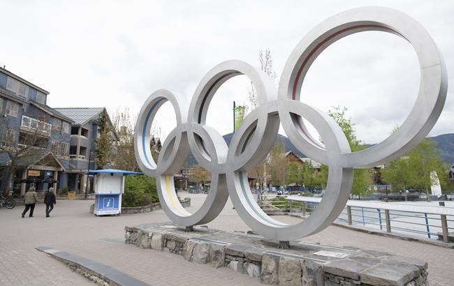 People walk past the Olympic rings in Whistler, B.C., Friday, May 15, 2020. An Indigenous-led partnership has taken the next step in exploring a potential bid to host the 2030 Winter Olympics and Paralympics. THE CANADIAN PRESS/Jonathan Hayward