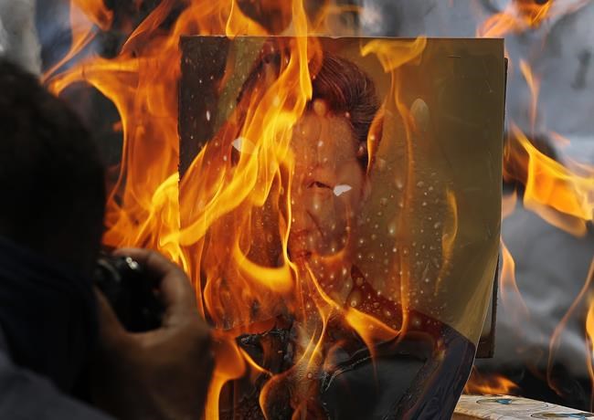 FILE- Indian traders reacting to the killing of Indian troops in a clash with Chinese soldiers in eastern Ladakh burn Chinese products and a poster president Xi Jinping during a protest in New Delhi, India, June 22, 2020. India will stay away from the opening and closing ceremonies of the Beijing Winter Olympics with an Indian official accusing China of politicizing the event. India objected to China using a soldier involved in fighting with Indian forces in Eastern Ladakh as a torchbearer for the Olympics ceremony. (AP Photo/Manish Swarup, File)