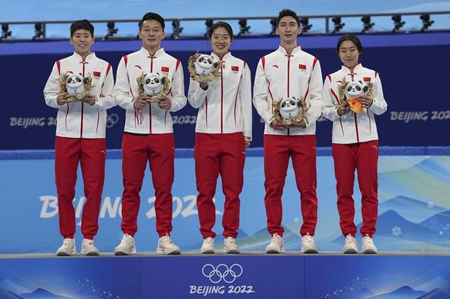 Team China celebrate on the podium after winning the gold medal in the mixed team relay during the short track speedskating competition at the 2022 Winter Olympics, Saturday, Feb. 5, 2022, in Beijing. (AP Photo/David J. Phillip)