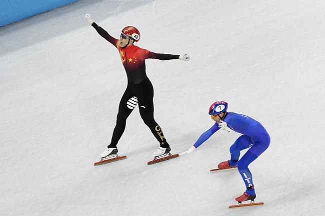 Wu Dajing, left, of China, celebrates after crossing the finish line ahead of Pietro Sighel, of Italy, to earn a gold medal for his team in the mixed relay short track speedskating competition at the 2022 Winter Olympics, Saturday, Feb. 5, 2022, in Beijing. (AP Photo/Jeff Roberson)