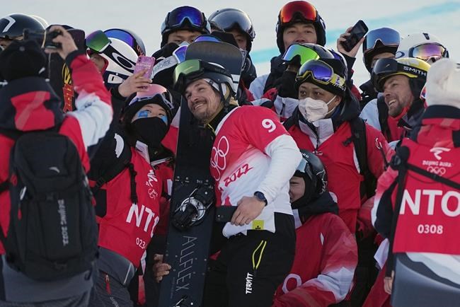 Bronze medalist Victor Wild, of the Russian Olympic Committee, and gold medalist Austria's Benjamin Karl, right, pose for a picture with volunteers during the venue ceremony for the men's parallel giant slalom at the 2022 Winter Olympics, Tuesday, Feb. 8, 2022, in Zhangjiakou, China. (AP Photo/Gregory Bull)