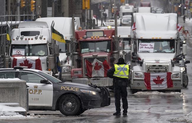 Police man a barricade in front of vehicles parked as part of the trucker protest, Tuesday, Feb. 8, 2022 in Ottawa’s downtown core. Ottawa's city manager says all tow-companies on contract with the city have refused to haul away the large trucks that have gridlocked Ottawa's downtown for the second week in a row. THE CANADIAN PRESS/Adrian Wyld