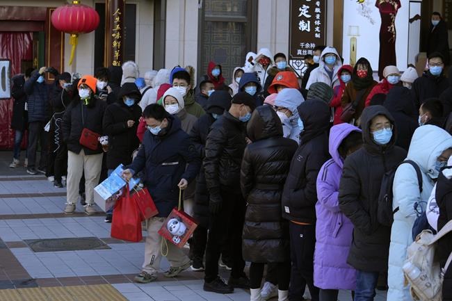 A resident carries away his purchase of 2022 Winter Olympics memorabilia including mascot Bing Dwen Dwen after lining up outside a store in Beijing, China, Friday, Feb. 4, 2022. (AP Photo/Ng Han Guan)