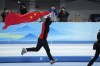 Tingyu Gao of China carries his country's flag after winning the gold medal and setting an Olympic record in the men's speedskating 500-meter race at the 2022 Winter Olympics, Saturday, Feb. 12, 2022, in Beijing. (AP Photo/Ashley Landis)