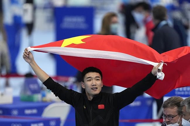 Tingyu Gao of China carries his country's flag after winning the gold medal and setting an Olympic record in the men's speedskating 500-meter race at the 2022 Winter Olympics, Saturday, Feb. 12, 2022, in Beijing. (AP Photo/Ashley Landis)