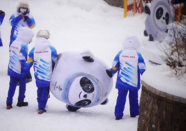 Volunteers carry an inflatable of Bing Dwen Dwen, the mascot of the 2022 Winter Olympics, at the sliding center, Sunday, Feb. 13, 2022, in the Yanqing district of Beijing. (AP Photo/Dmitri Lovetsky)