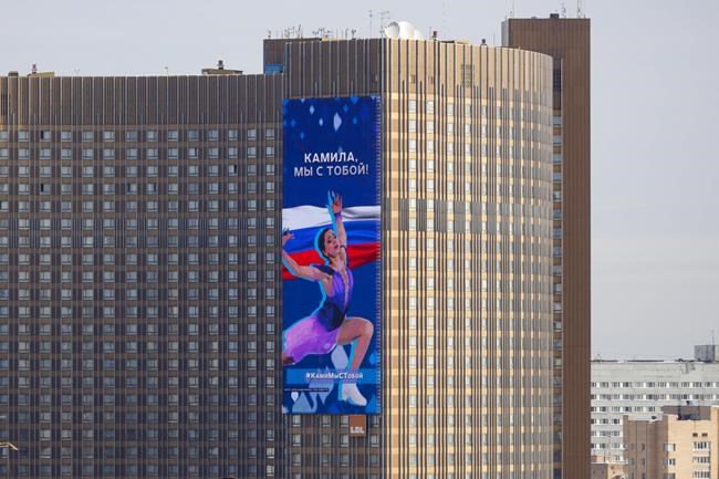 A huge electronic billboard shows a photo of Kamila Valieva with words