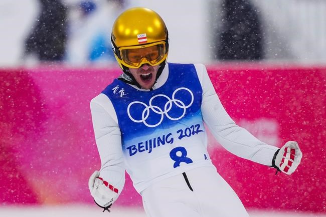 Franz-Josef Rehrl, of Austria, celebrates after his jump during the team Gundersen large hill/4x5km ski jumping competition round at the 2022 Winter Olympics, Thursday, Feb. 17, 2022, in Zhangjiakou, China. (AP Photo/Matthias Schrader)