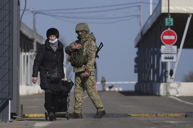 A woman crosses a checkpoint from the territory controlled by Russia-backed separatists to the territory controlled by Ukrainian forces in Novotroitske, eastern Ukraine, Monday, Feb. 21, 2022. World leaders are making another diplomatic push in hopes of preventing a Russian invasion of Ukraine, even as heavy shelling continues in Ukraine’s east. (AP Photo/Evgeniy Maloletka)