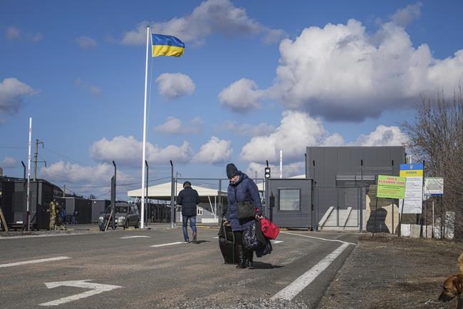 A woman walks after crossing a checkpoint from territory controlled by Russia-backed separatists to the territory controlled by Ukrainian forces in Novotroitske, eastern Ukraine, Monday, Feb. 21, 2022. World leaders are making another diplomatic push in hopes of preventing a Russian invasion of Ukraine, even as heavy shelling continues in Ukraine's east. (AP Photo/Evgeniy Maloletka)