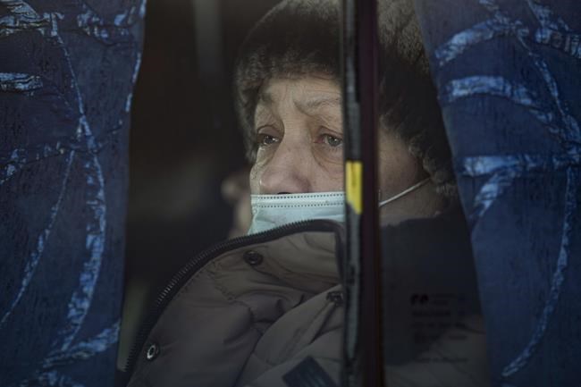 A woman sits on a bus after crossing from pro-Russian separatists controlled territory to Ukrainian government controlled areas, in Stanytsia Luhanska, the only crossing point open daily, in the Luhansk region, eastern Ukraine, Tuesday, Feb. 22, 2022. Russia says its recognition of independence for areas in eastern Ukraine extends to territory currently held by Ukrainian forces. The statement Tuesday further raises the stakes amid Western fears that Moscow could follow up to Monday’s recognition of rebel regions with a full-fledged invasion of Ukraine. (AP Photo/Vadim Ghirda)