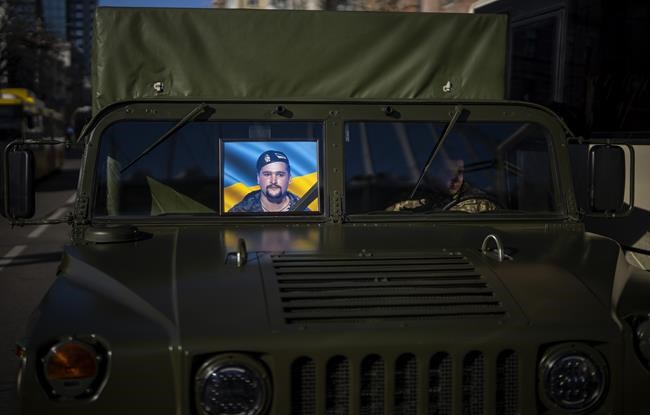 A photo of Ukrainian army captain Anton Sydorov, 35, killed in eastern Ukraine, is displayed in a military vehicle carrying his body during his funeral, in Kyiv, Tuesday, Feb. 22, 2022. Western leaders said Tuesday that Russian troops have moved into rebel-held areas in eastern Ukraine after President Vladimir Putin’s recognized their independence — but some indicated it was not yet the long-feared full-fledged invasion as confusion reigned in the region. (AP Photo/Emilio Morenatti)