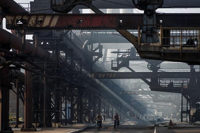 FILE - Workers walk and cycle along the coal transporters at the front-line Avdiivka coking plant in eastern Ukraine, Tuesday, Aug. 4, 2015. The squeezing of Ukraine's economy is a key destabilizing tactic in what the government describes as