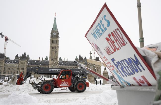 Machinery moves a concrete barricade past the Parliament buildings and a container of garbage from the Trucker protest which has occupied the streets of Ottawa, Sunday, February 20, 2022. THE CANADIAN PRESS/Adrian Wyld