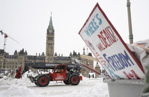 Machinery moves a concrete barricade past the Parliament buildings and a container of garbage from the Trucker protest which has occupied the streets of Ottawa, Sunday, February 20, 2022. THE CANADIAN PRESS/Adrian Wyld