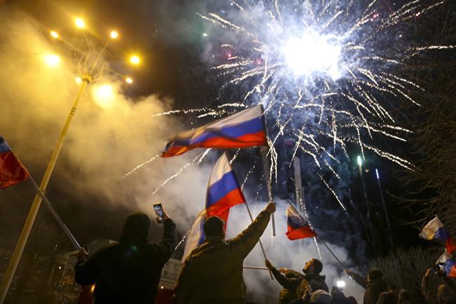 FILE - People wave Russian national flags celebrating the recognizing the independence in the center of Donetsk, the territory controlled by pro-Russian militants, eastern Ukraine, late Monday, Feb. 21, 2022. Channel One, another popular state-funded TV station, struck a more festive tone in a news bulletin on Tuesday morning, with a correspondent in Donetsk telling the news presenter that local residents