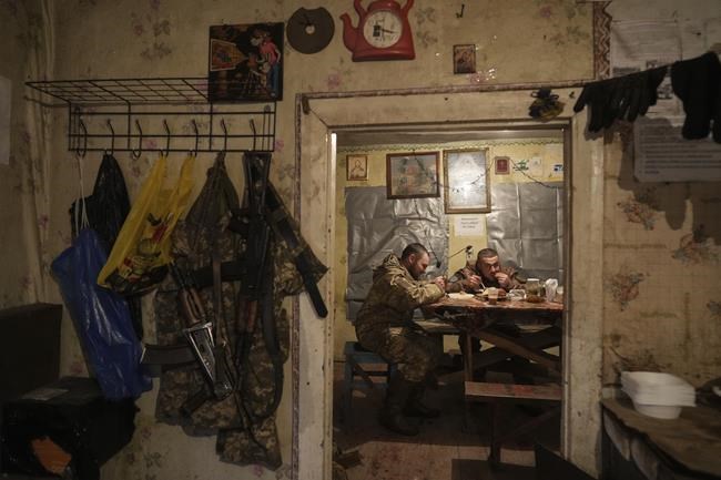 Ukrainian servicemen eat dinner after their duty at the frontline near Svitlodarsk, eastern Ukraine, Wednesday, Feb. 23, 2022. U.S. President Joe Biden announced the U.S. was ordering heavy financial sanctions against Russia, declaring that Moscow had flagrantly violated international law in what he called the
