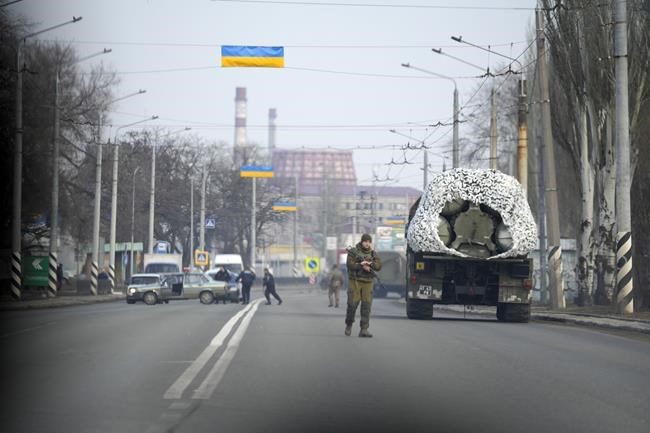 A Ukrainian soldier stands next to a military vehicle on a road in Kramatosrk, eastern Ukraine, Thursday, Feb. 24, 2022. Russian troops launched a wide-ranging attack on Ukraine on Thursday. President Vladimir Putin cast aside international condemnation and sanctions and warned other countries that any attempt to interfere would lead to