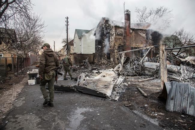 Ukrainian servicemen walk at fragments of a downed aircraft seen in in Kyiv, Ukraine, Friday, Feb. 25, 2022. It was unclear what aicraft crashed and what brought it down amid the Russian invasion in Ukraine Russia is pressing its invasion of Ukraine to the outskirts of the capital after unleashing airstrikes on cities and military bases and sending in troops and tanks from three sides. (AP Photo/Oleksandr Ratushniak)