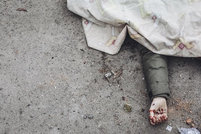 The dead body of a person killed by Russian shelling lays covered in the street in the town of Irpin, Ukraine, Sunday, March 6, 2022. With the Kremlin's rhetoric growing fiercer and a reprieve from fighting dissolving, Russian troops continued to shell encircled cities and the number of Ukrainians forced from their country grew to over 1.4 million. (AP Photo/Diego Herrera Carcedo)